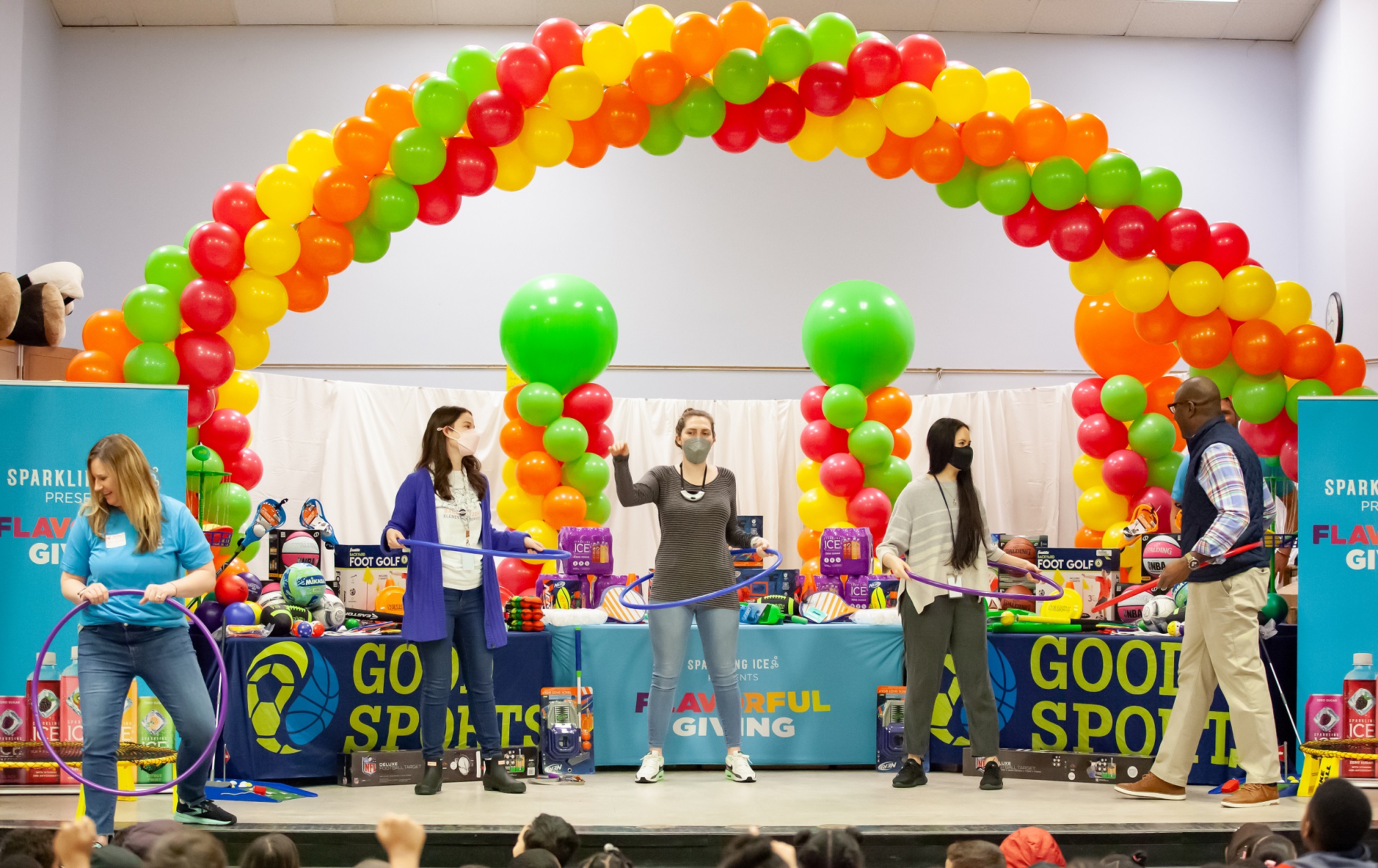 Teachers and volunteers compete in hula hoop contest on stage