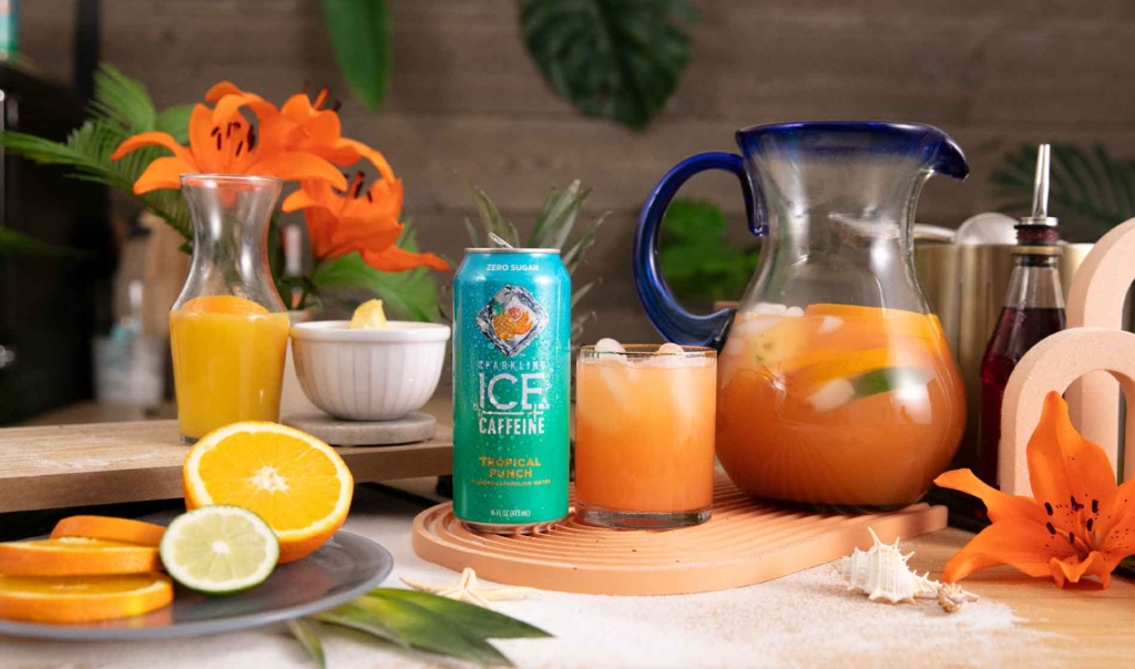 Sparkling Sunrise Mocktail drink from Sparkling Ice in an ice-filled glass with a glass pitcher and orange slice.