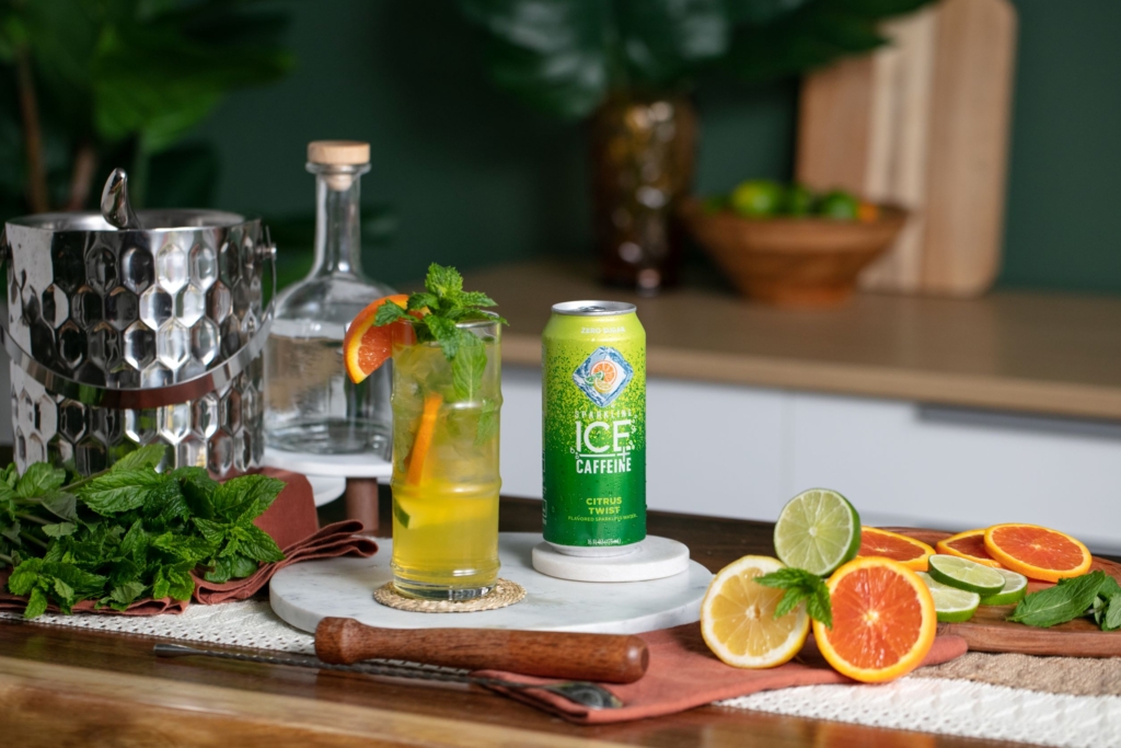 Sparkling Ice Citrus Twist Mojito cocktail on a table with freshly sliced oranges and lime.
